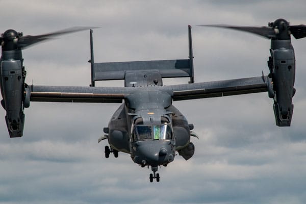 A V-22 Osprey military aircraft flying in a cloudy sky