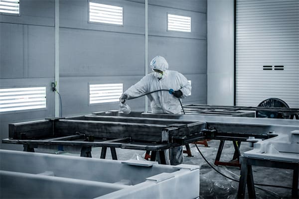 A worker paints large metal fabrications