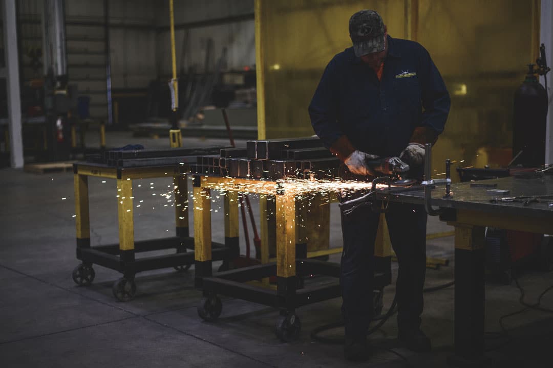 A fabricator grinding a component for large tooling or parts for the heavy equipment industry