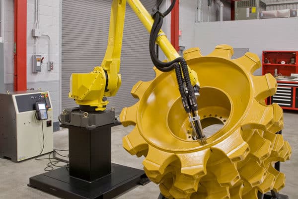 An automated robotic welding system welds a wheel for heavy equipment