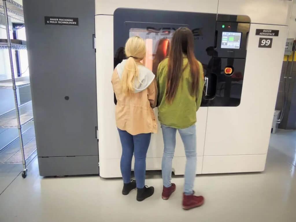Students looking into an FDM 3D printer at Baker Industries