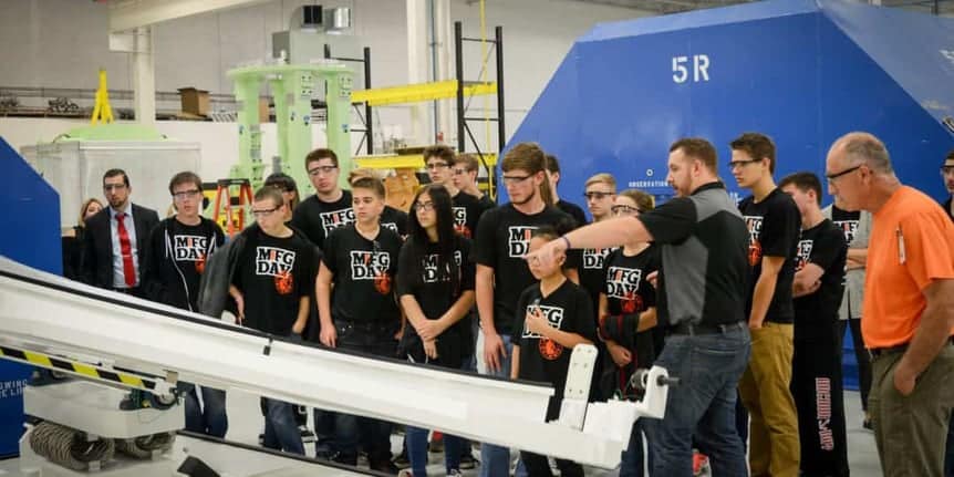 Students gathered around aerospace tooling at Baker Industries during MFG Day 2016