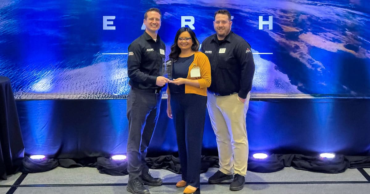 Mark Laesch and Brian Baker from Baker Industries pose with a member of the Blue Origin team and Baker's Environmental Award at the 2024 Supplier Summit: Revolution Lunar.