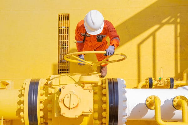 A worker performing repairs or maintenance on an offshore oil and gas drilling rig