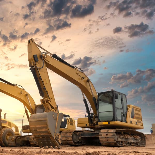 Yellow excavators in front of a sunset
