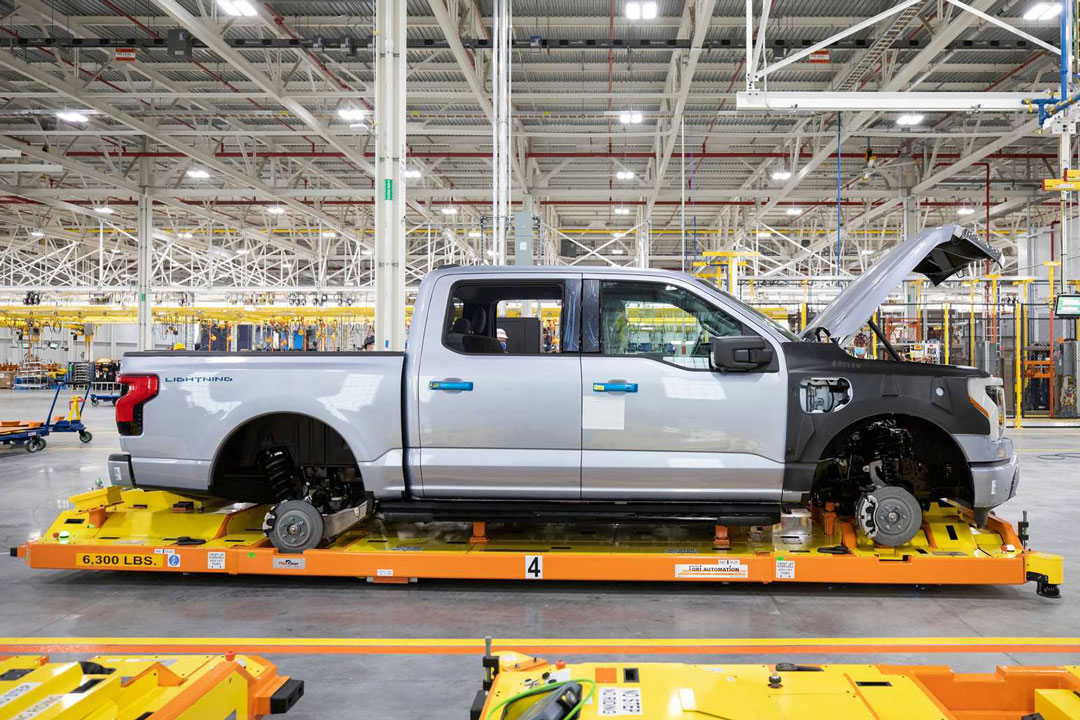 A silver Ford F-150 truck being carried through Ford's factory by a Fori Automation Automated Guided Vehicle (AGV)