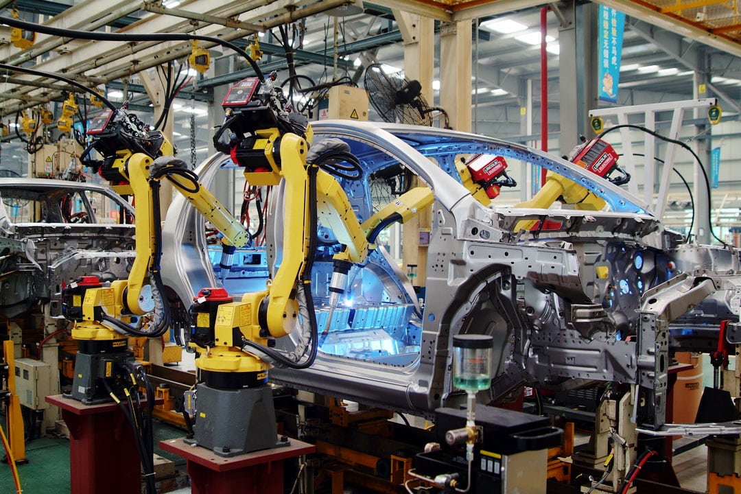 An image of a vehicle manufacturing line, featuring Lincoln Electric welding robots welding a sedan body