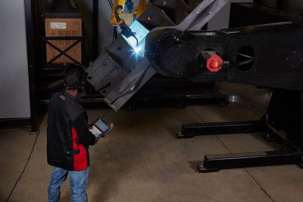 A robotic welder welding a metal component for the shipbuilding industry