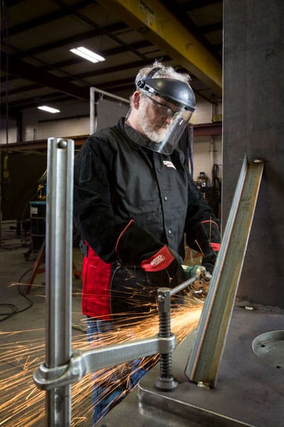 A fabricator grinding a large metal workpiece